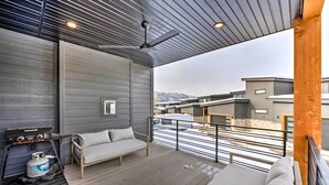 Ett modernt utomhusområde med en soffa, en grill och utsikt över de omgivande byggnaderna.