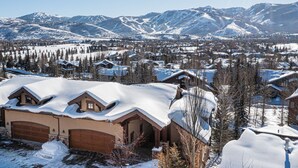 Un pueblo cubierto de nieve con casas de estilo chalete, una pista de esquí y una vista despejada de las montañas circundantes.