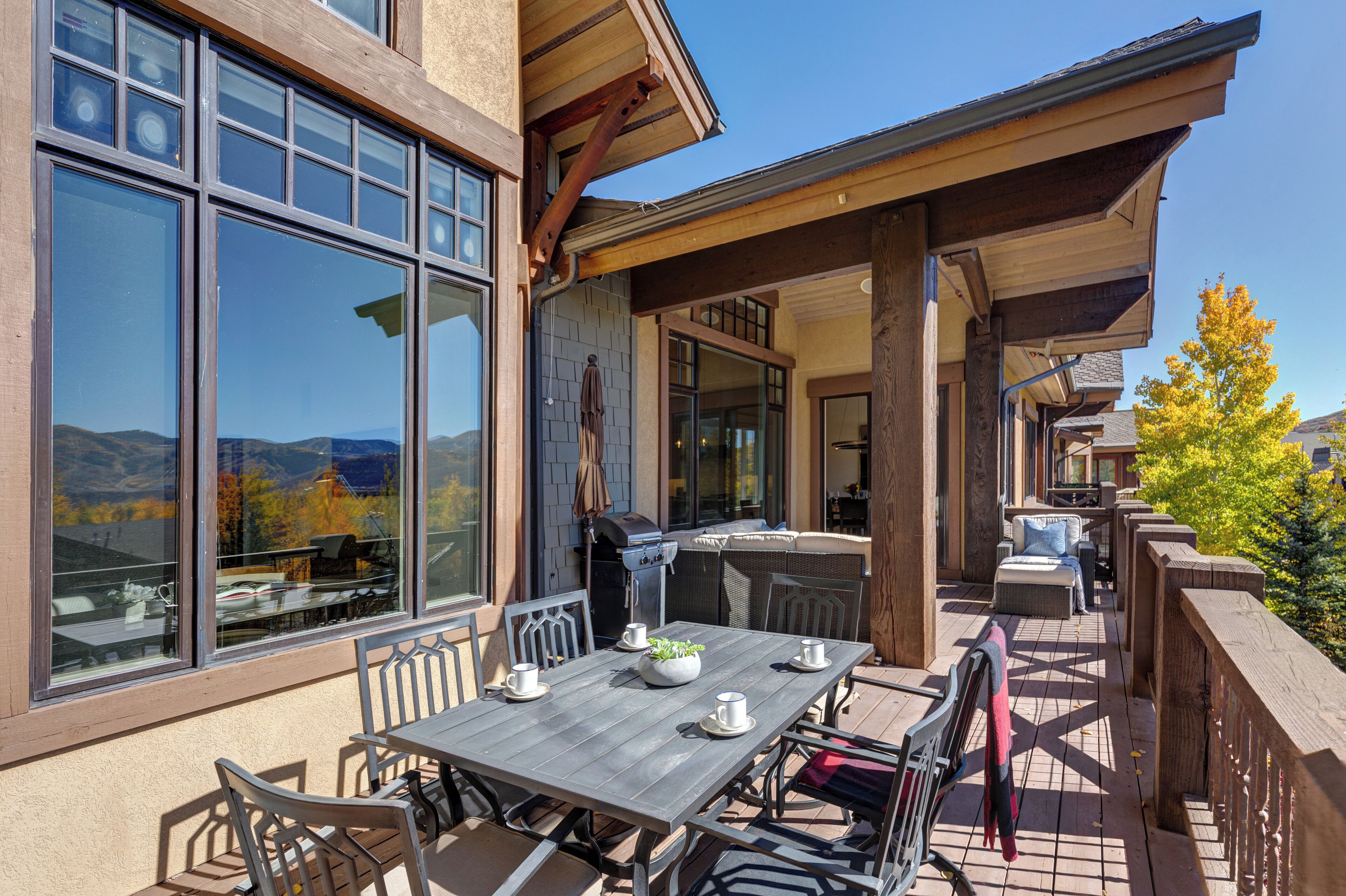 Une terrasse extérieure avec une table à manger, des chaises et un barbecue.