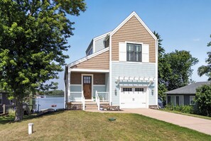 A two-story house with a front porch, a garage, and a small front yard.