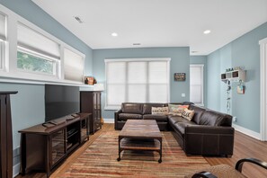 A living room with a dark brown leather sofa, a wooden coffee table, a flat-screen TV, and a fireplace.