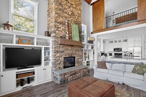 A spacious living room with a stone fireplace, a television, and a cozy seating area.