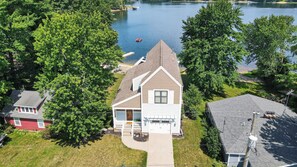 A two-story house with a steep gable roof, a front porch, and a driveway leading to a garage.