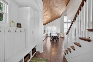 A spacious hallway with a wooden ceiling, white walls, and a dining area with a large table and chairs.