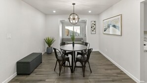 Un comedor moderno con una mesa redonda, cuatro sillas, un banco y una planta en maceta.