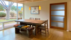 A dining area with a large wooden table, cushioned benches, and pendant lighting.