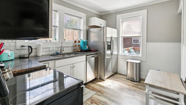 Una cocina moderna con electrodomésticos de acero inoxidable, armarios blancos y suelo de madera.