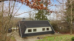 A small, modern house with a sloped roof, surrounded by trees and a gravel driveway. - Ferienhaus schöne Aussicht (Gerolstein)