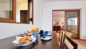 Un desayuno con cruasanes, jugo de naranja y tazas de café sobre una mesa de madera.
