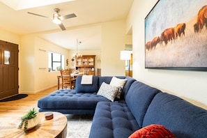 Ein Wohnzimmer mit Ecksofa, Essbereich und einer Chandelier.