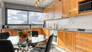 Eine moderne Küche mit Holzausstattung, einem Glastisch und einem großen Fenster.