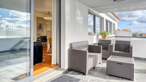 Ein moderner Balkon mit Rattanmöbeln, einem Blumentopf und Blick auf die Stadtlandschaft.