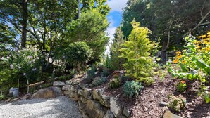 A garden with a gravel path, various plants, and a stone wall. - Mountain Cottage on Ski Slopes (Blowing Rock)