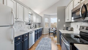 A modern kitchen with white cabinets, a stainless steel refrigerator, a microwave, and a stove. - Mountain Cottage on Ski Slopes (Blowing Rock)