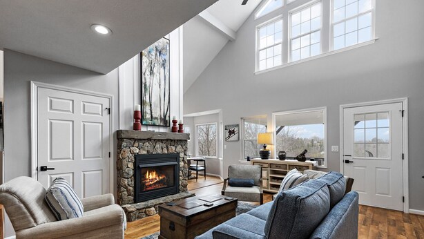 A spacious living room with a stone fireplace, two armchairs, a sofa, and a coffee table. - Mountain Cottage on Ski Slopes (Blowing Rock)