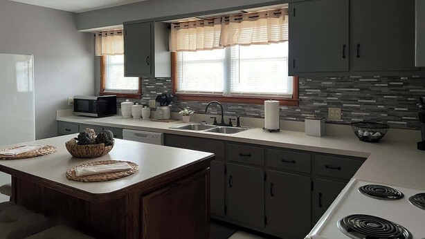 A modern kitchen with grey cabinets, a white countertop, and a central island.
