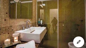 Un bagno con uno specchio grande, un lavandino bianco e un box doccia in vetro.