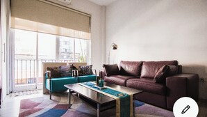 Un soggiorno con un divano in pelle marrone, un divano verde acqua con cuscini decorati e un tavolino da caffè.