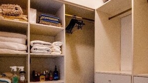 Un armadio a muro con mensole per asciugamani piegati, un appendiabiti e cassetti portaoggetti.