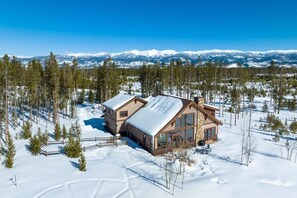 A cabin with a large window, a chimney, and a snow-covered landscape. - Moose Run Spacious Winter Park Area Retreat (Fraser)
