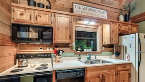 A kitchen with wooden cabinets, a stove, a microwave, and a refrigerator.