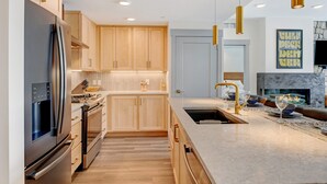 A modern kitchen with wooden cabinets, stainless steel appliances, and a marble countertop.