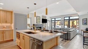 A modern kitchen with a large island, built-in appliances, and a dining area with a sofa and table.