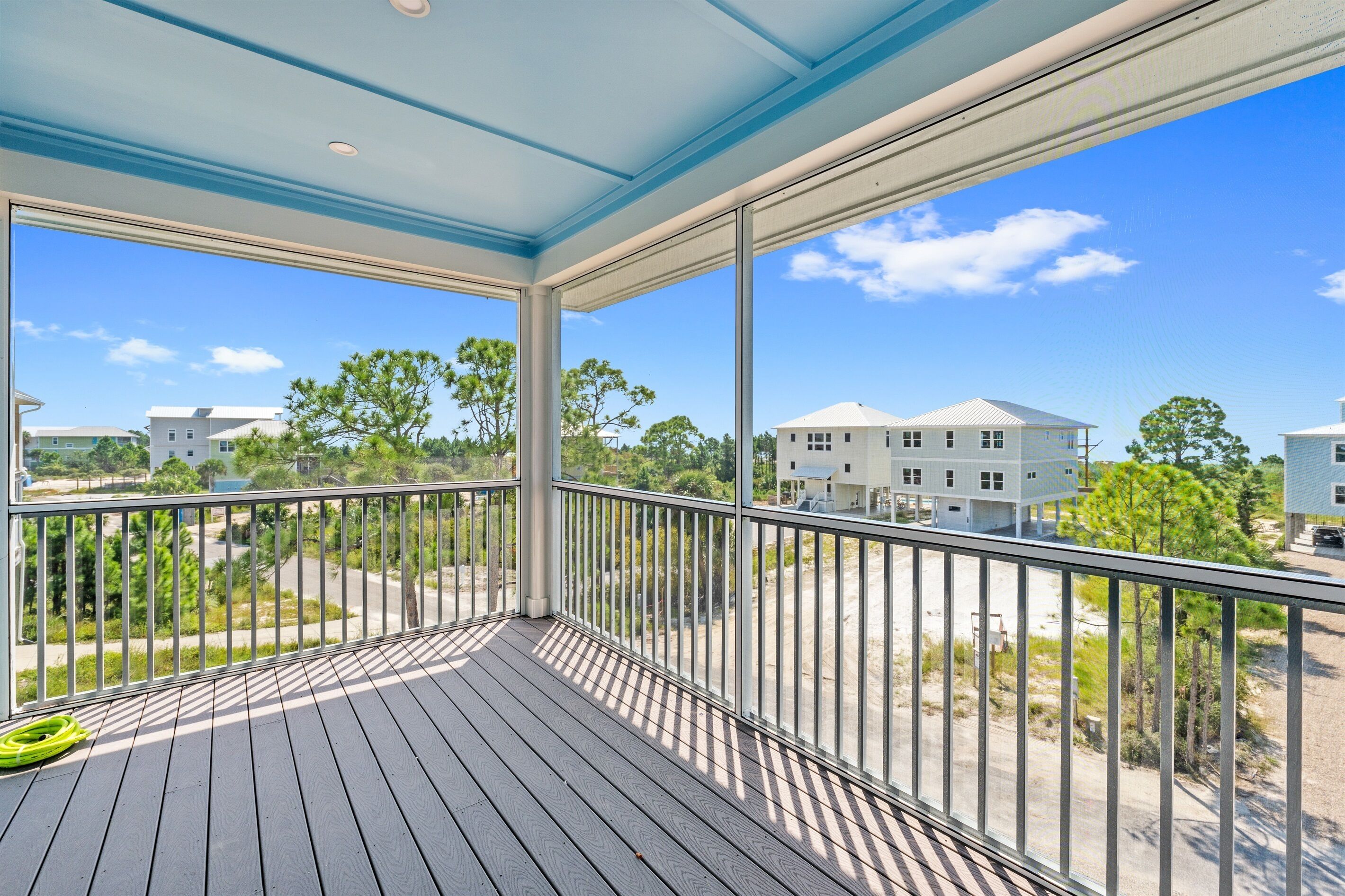 A covered balcony with a view of neighboring houses and trees.