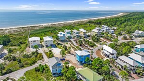 Uma área residencial costeira com casas, uma praia e vista clara para o oceano.
