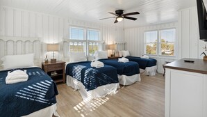 Une chambre d’hôtel avec deux lits, un ventilateur de plafond, une télévision et un bureau.