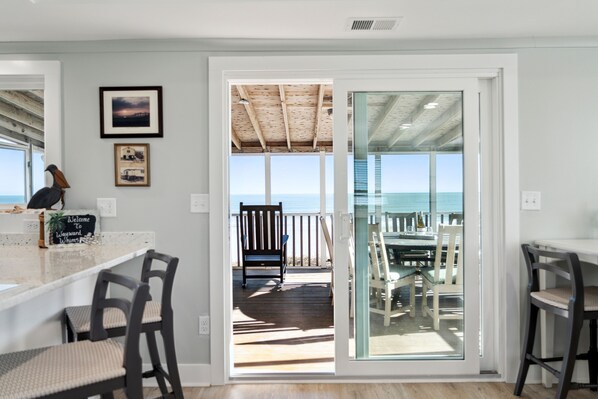 A modern kitchen with a view of the ocean through a sliding glass door.
