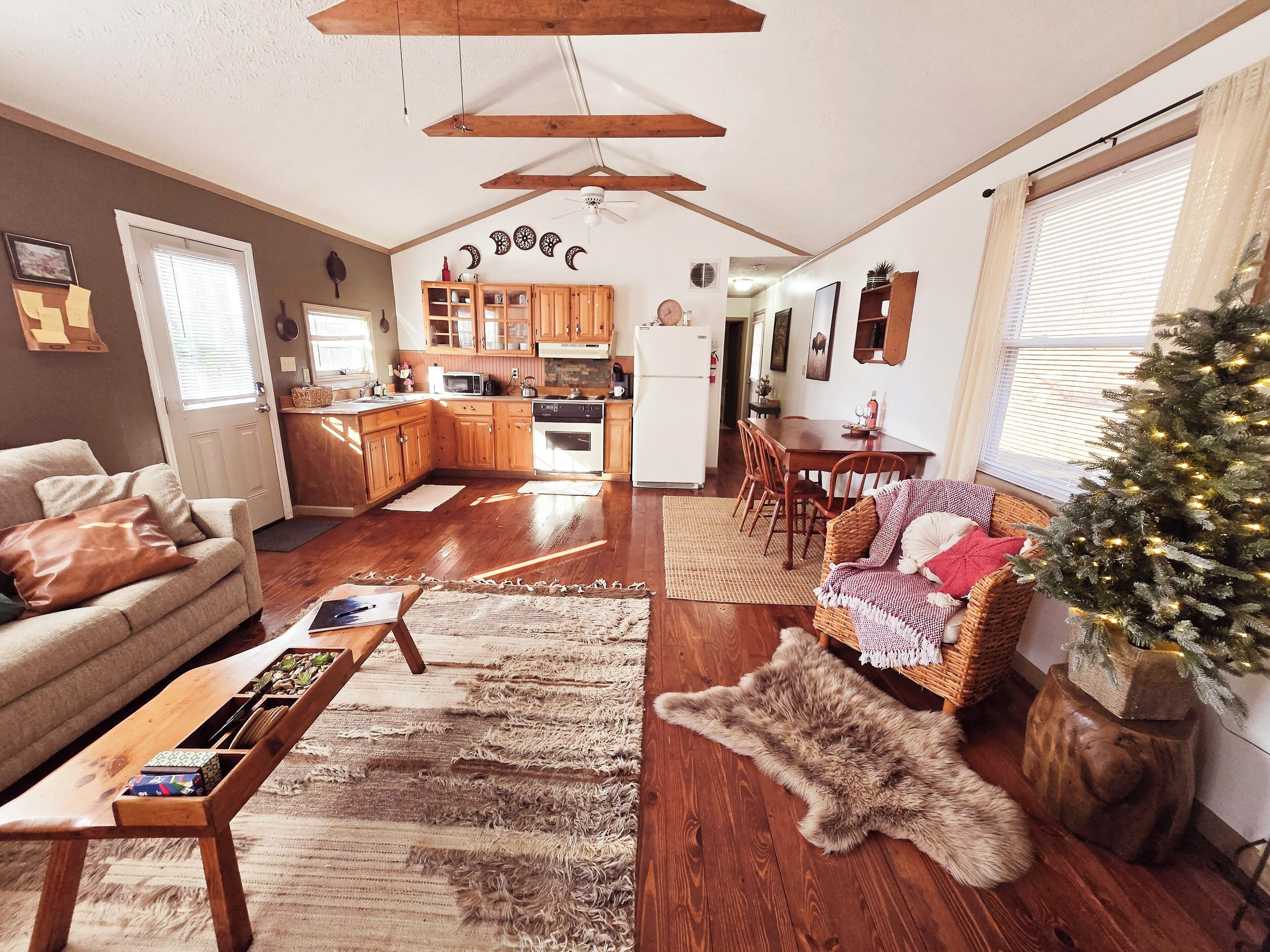 A cozy living room with a sofa, coffee table, and a Christmas tree.