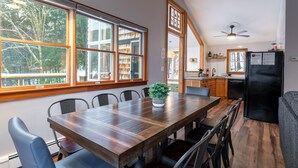 A spacious kitchen with large windows, a dining area with a wooden table, and a black refrigerator. - Secluded/Hot Tub/views! Minutes to Everything! (Bridgewater Corners)