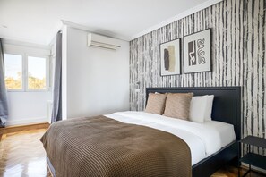 Relax in this serene bedroom with a large bed, framed artworks, and a cozy nightstand.