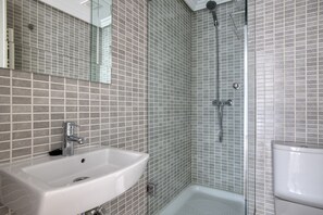 Bathroom features a large sink, glass-enclosed shower, and toilet.