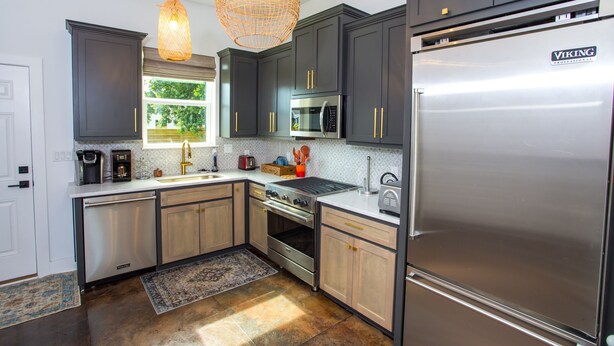A modern kitchen with dark cabinets, stainless steel appliances, and a large refrigerator.