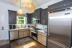 A modern kitchen with dark cabinets, stainless steel appliances, and a large refrigerator.