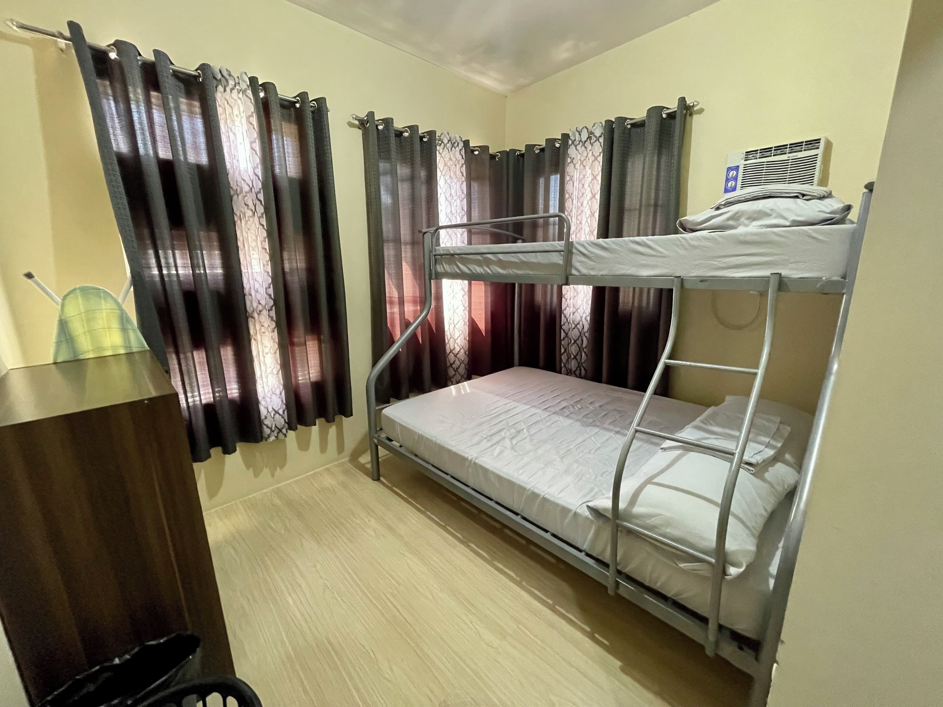A bunk bed room with a desk and curtains.