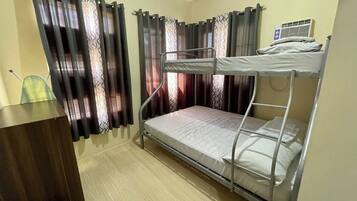 A bunk bed room with a desk and curtains.