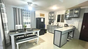 A compact kitchen with a dining area, a refrigerator, a microwave, and a sink.