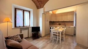 A compact living space with a sofa, TV, dining table, and kitchen area.