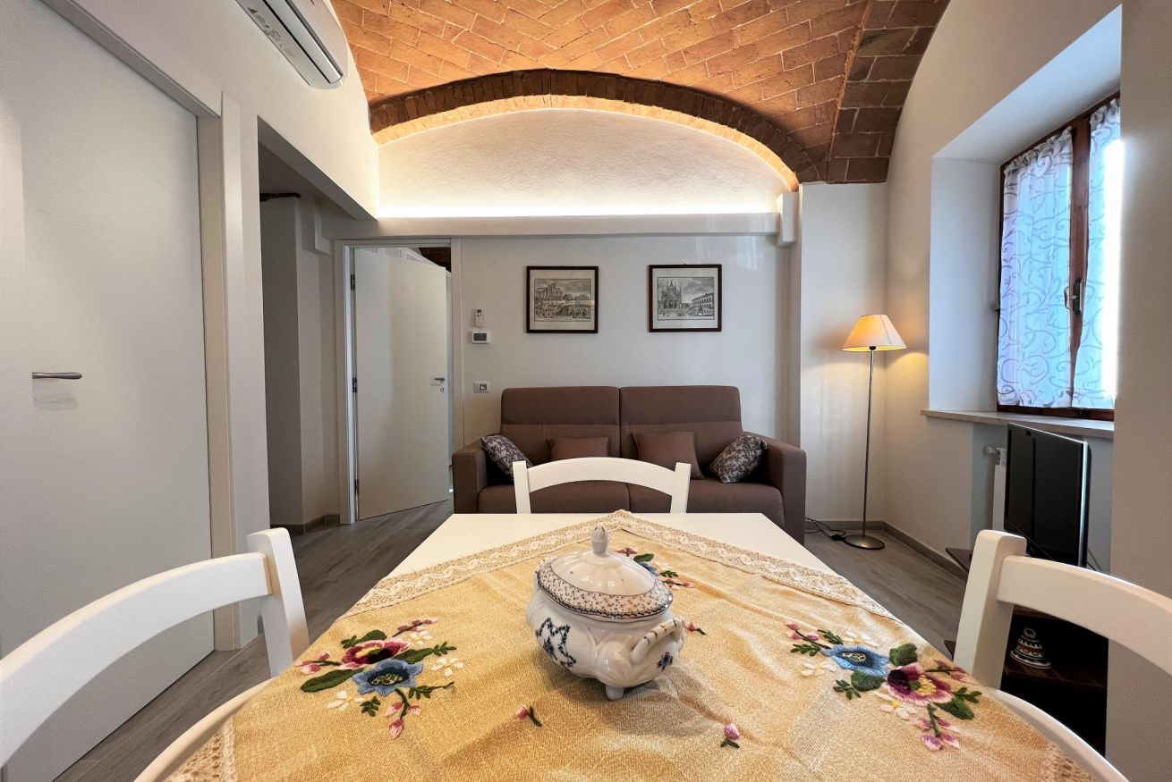 A dining area with a table set for two, a decorative teapot, and a sofa in the background.