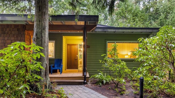 A small, green cabin with a wooden porch and a blue chair. - Island Beach House at Rathtrevor, Tucked in the forest and steps to the beach (Parksville)