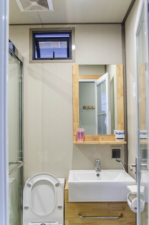 A modern bathroom with a toilet, sink, and mirror. - MORIYAMA HOTEL (Mandaue)