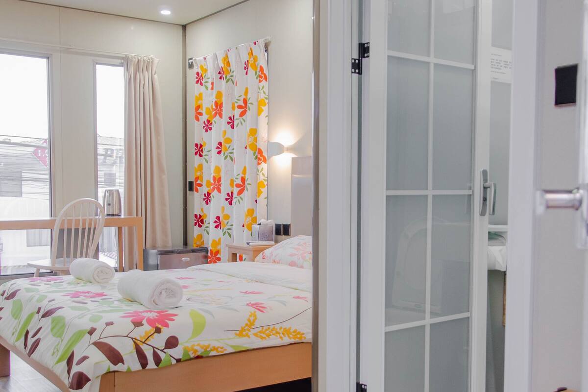 Una habitación de hotel moderna con cama, escritorio, silla y armario con puerta corredera.