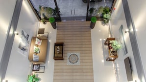 A spacious lobby with a central seating area, potted plants, and a decorative tile in the middle. - MORIYAMA HOTEL (Mandaue)