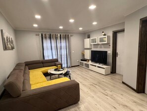 Relax in this stylish living room with a large sofa, coffee table, and flat-screen TV.
