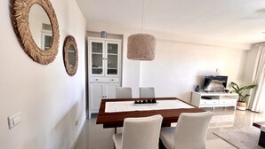 A modern dining area with a wooden table, white chairs, and a cabinet with glass doors. - 2-Bed Apt with Sea and views near Marbella, Spain (Calahonda)