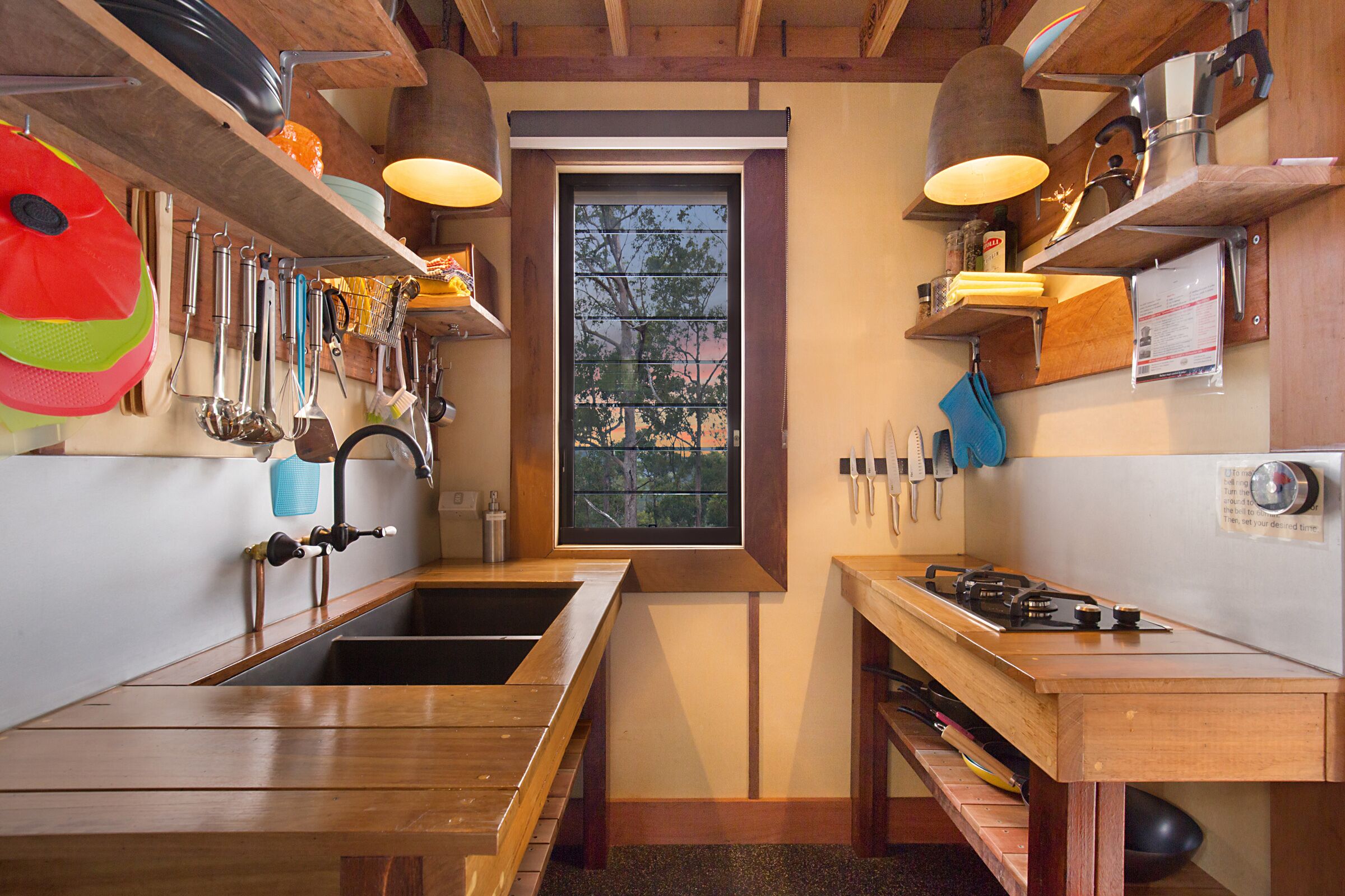 Una cucina compatta con piani in legno, un lavello doppio e una finestra vista alberi.