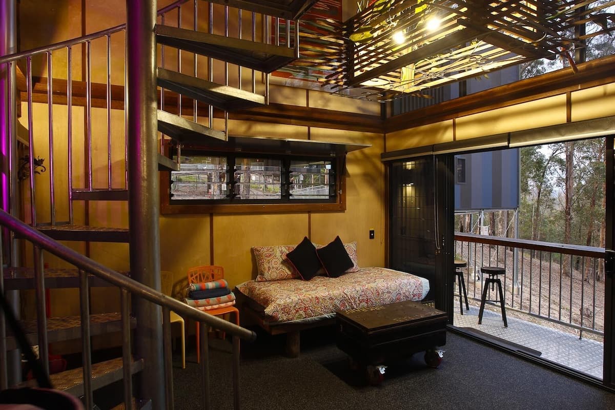 A cozy interior with a bed, a small table, and a staircase.